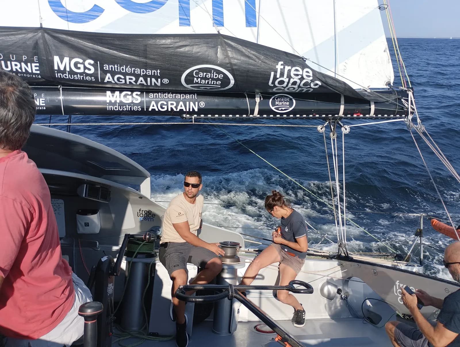 Équipage à bord d'un voilier de course, grand-voile sponsorisée hissée, au départ d'une régate